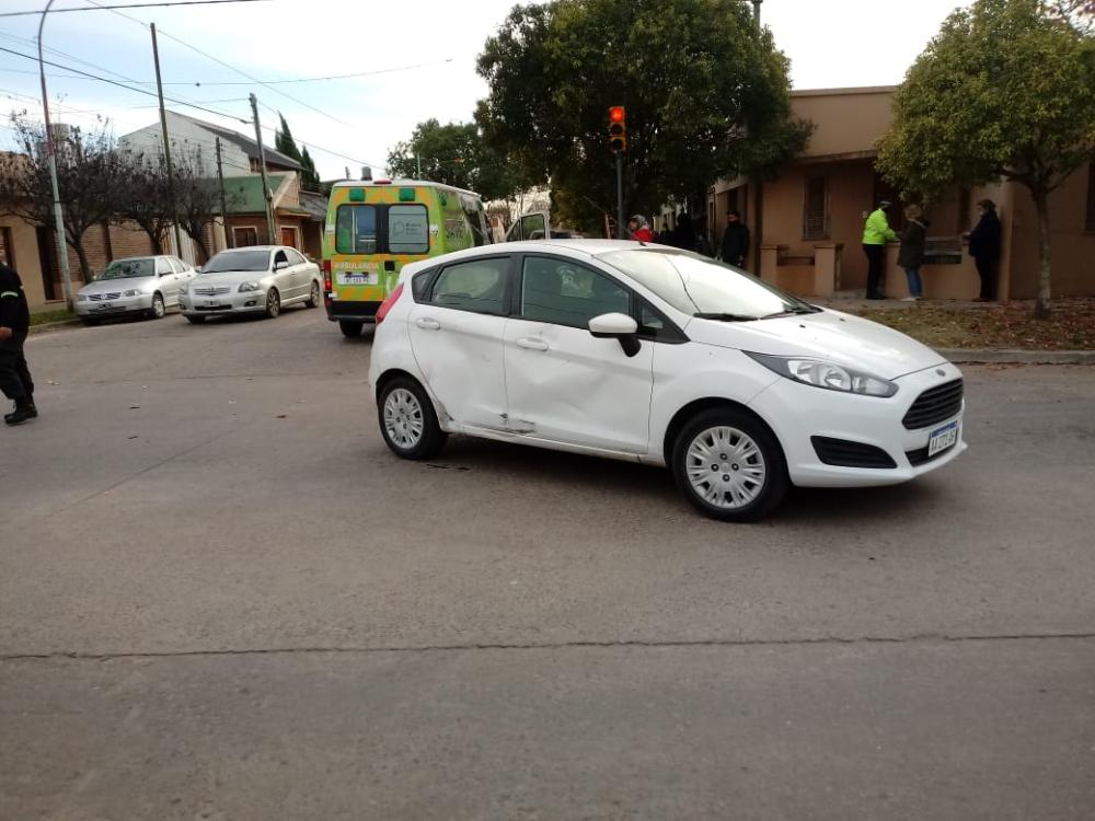 Fuerte colisión entre auto y moto en una esquina con semáforo